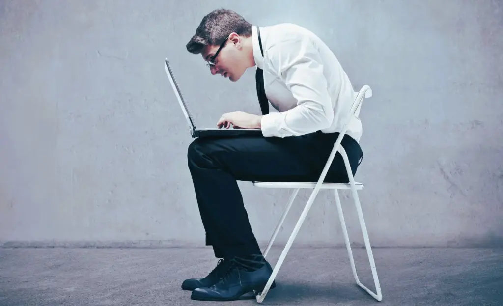 A hunched man is sitting on a chair